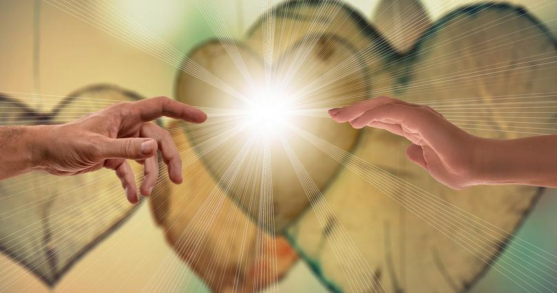 Two hands contacti through the light of love.